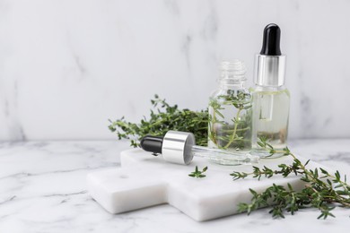 Photo of Thyme essential oil on white marble table, space for text