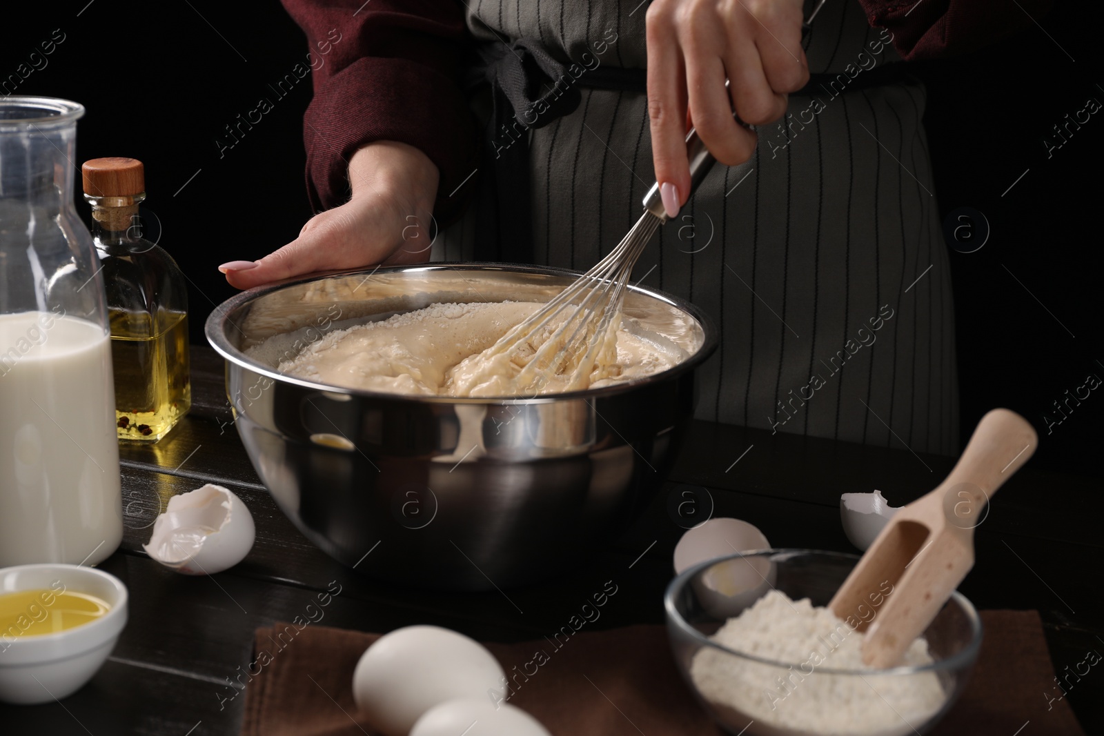 Photo of Woman making dough with whisk in bowl at table, closeup