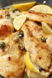 Photo of Delicious chicken piccata with lemons in pot, closeup