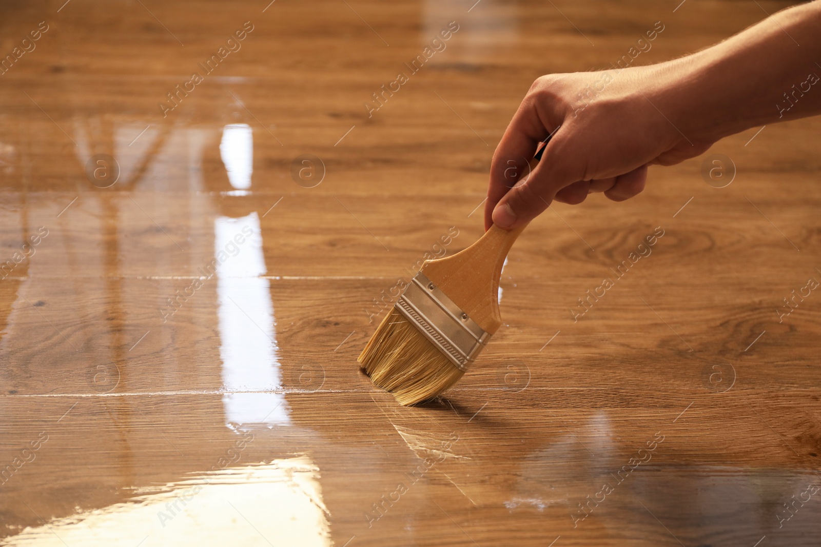 Photo of Woman with brush varnishing wooden surface, closeup