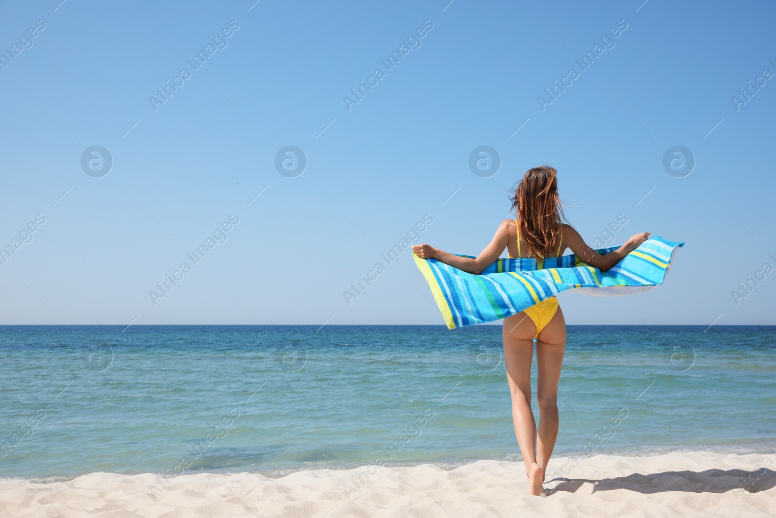 Photo of Woman with beach towel near sea on sunny day, back view