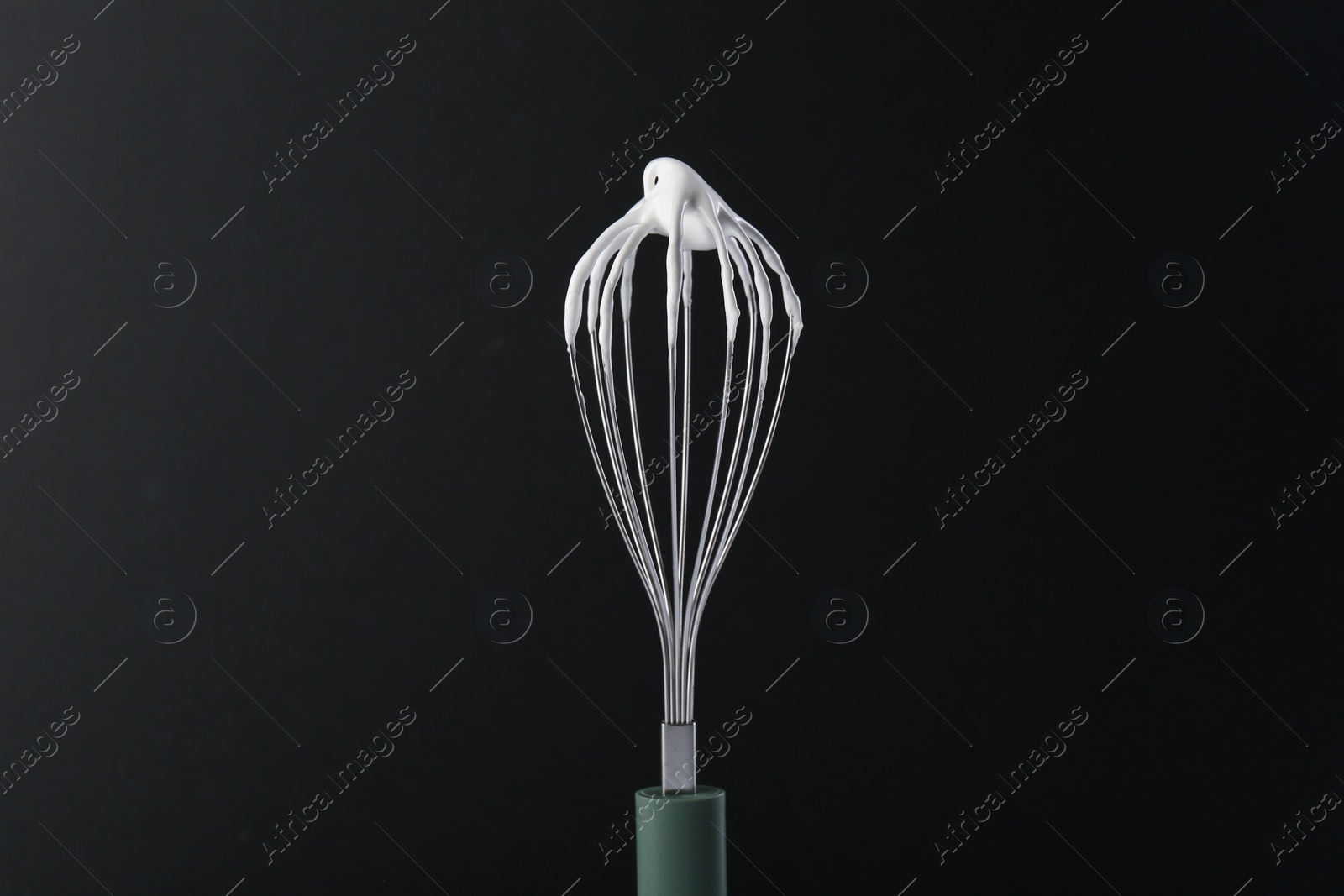 Photo of Whisk with whipped cream on black background