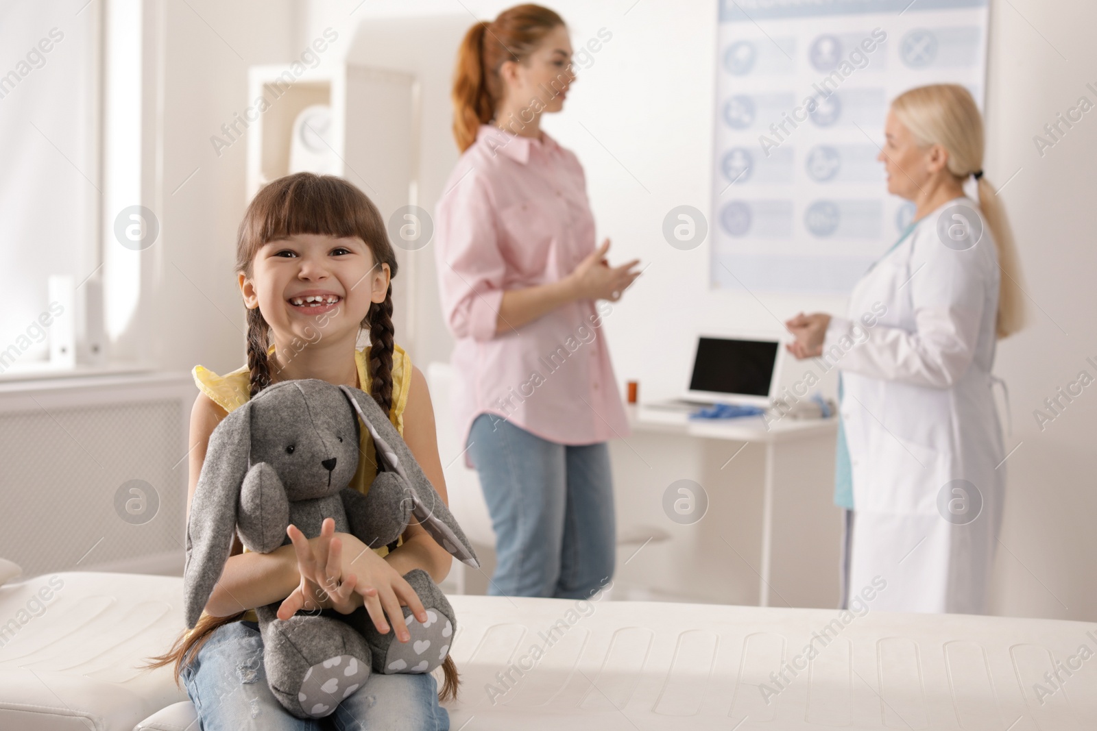 Photo of Adorable child with toy and mother visiting doctor at hospital