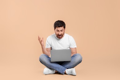Photo of Emotional man with laptop on beige background