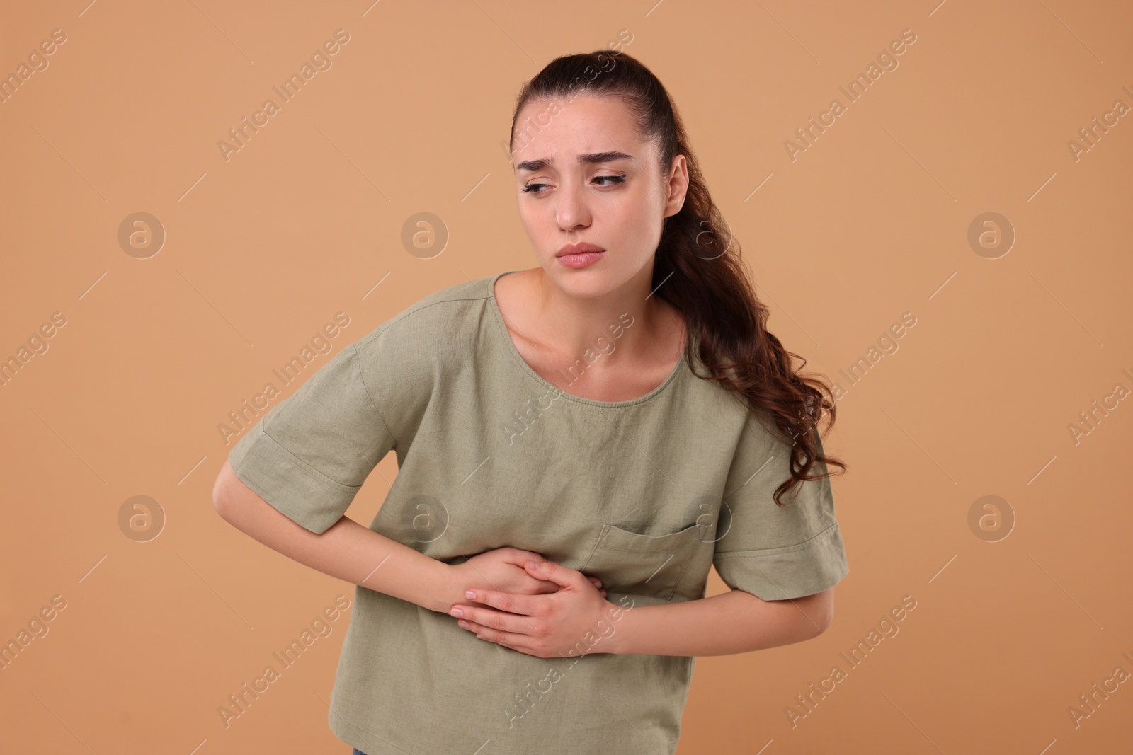 Photo of Woman suffering from abdominal pain on beige background. Unhealthy stomach