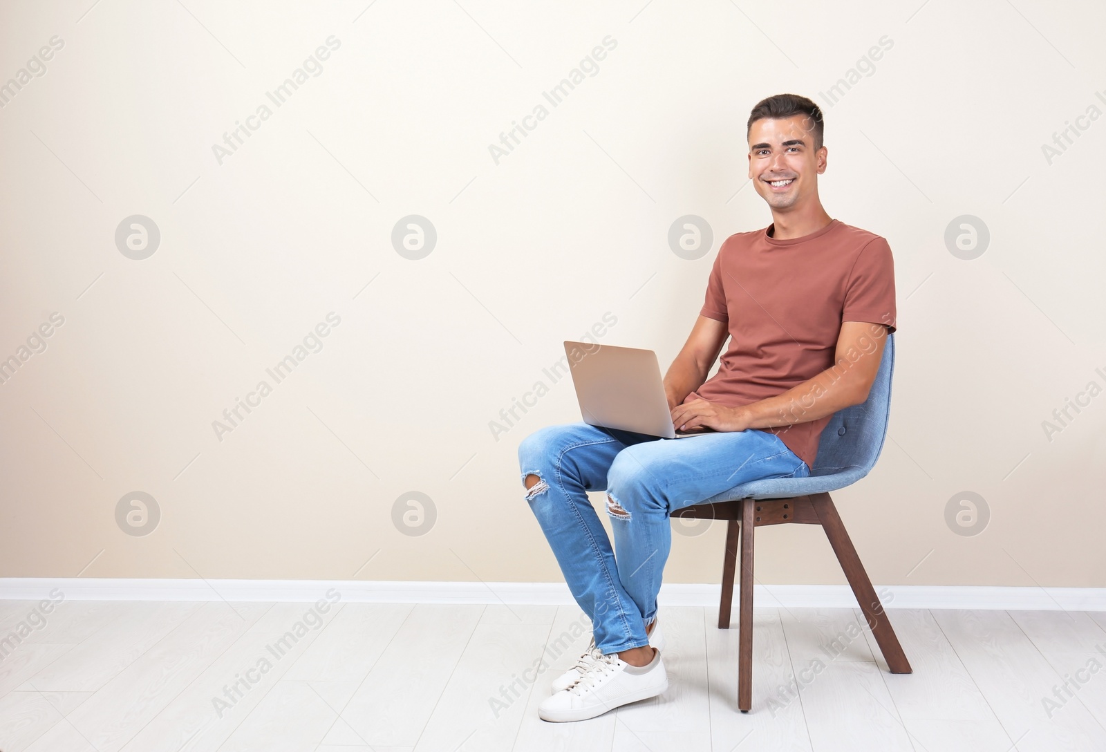 Photo of Man in casual clothes with laptop near color wall