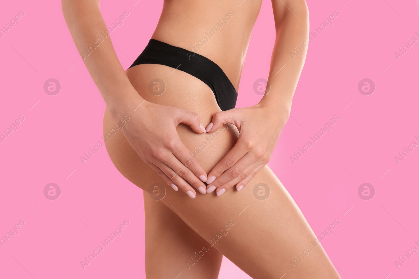 Photo of Closeup view of slim woman in underwear making heart with hands near thigh on color background. Cellulite problem concept