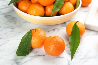 Fresh tangerines with green leaves on white marble table