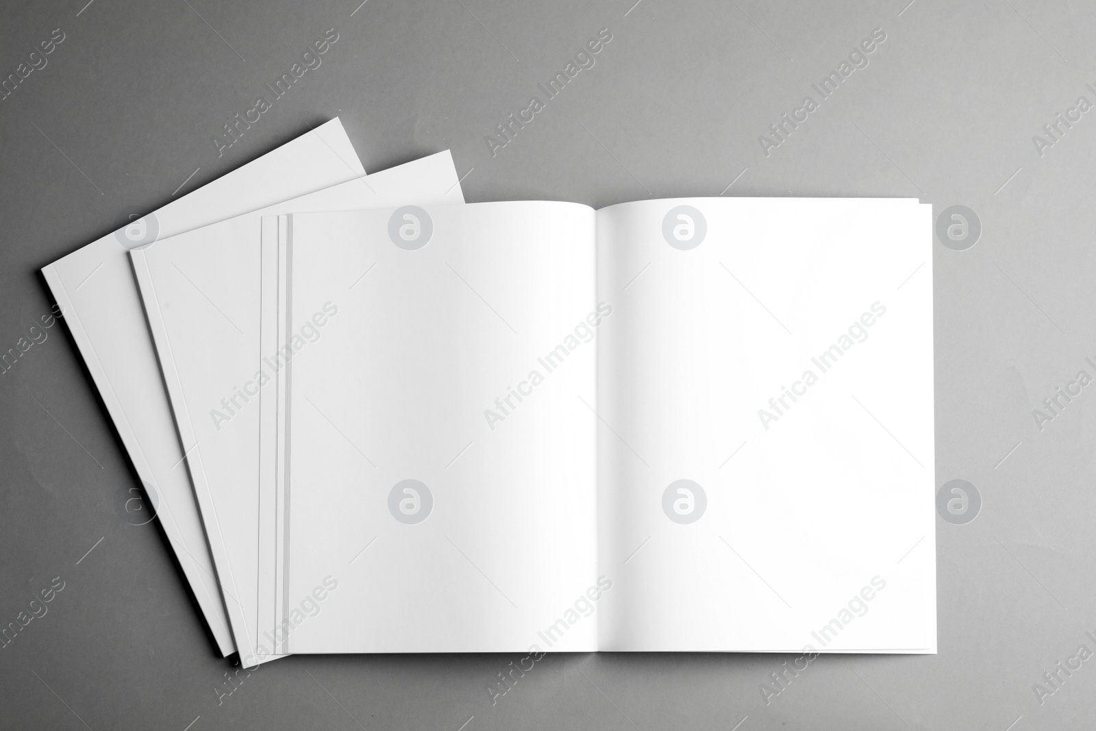 Photo of Open and closed blank brochures on grey background, top view. Mock up for design