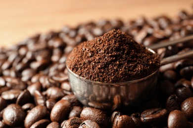 Photo of Spoon with coffee grounds and roasted beans on table, closeup