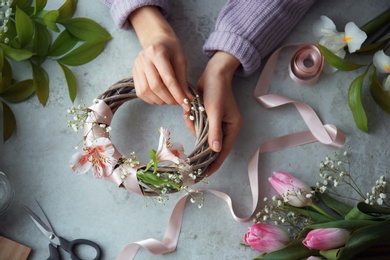 Photo of Female decorator creating beautiful wreath at table, top view