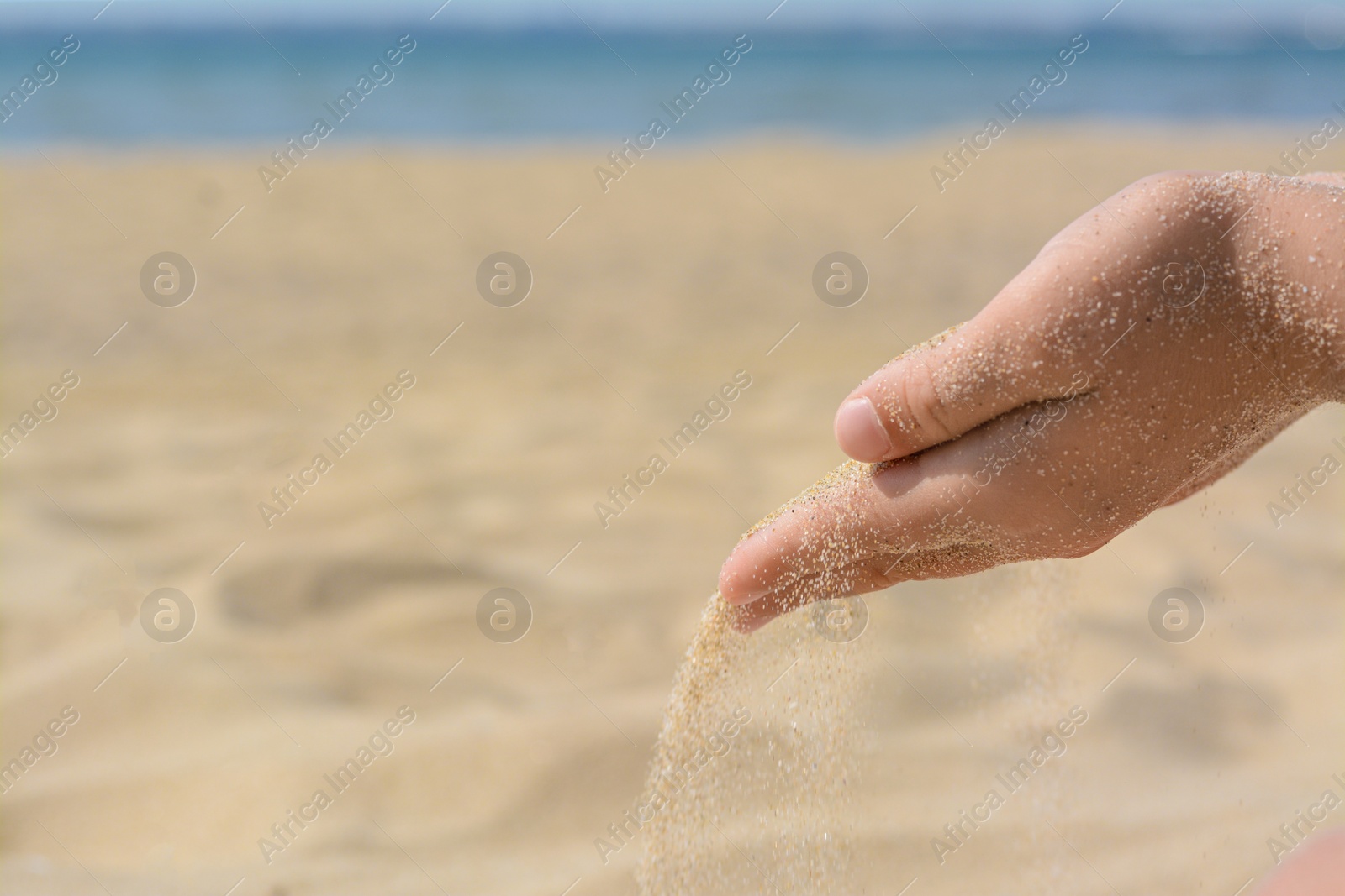 Photo of Child pouring sand from hand on beach, closeup with space for text. Fleeting time concept