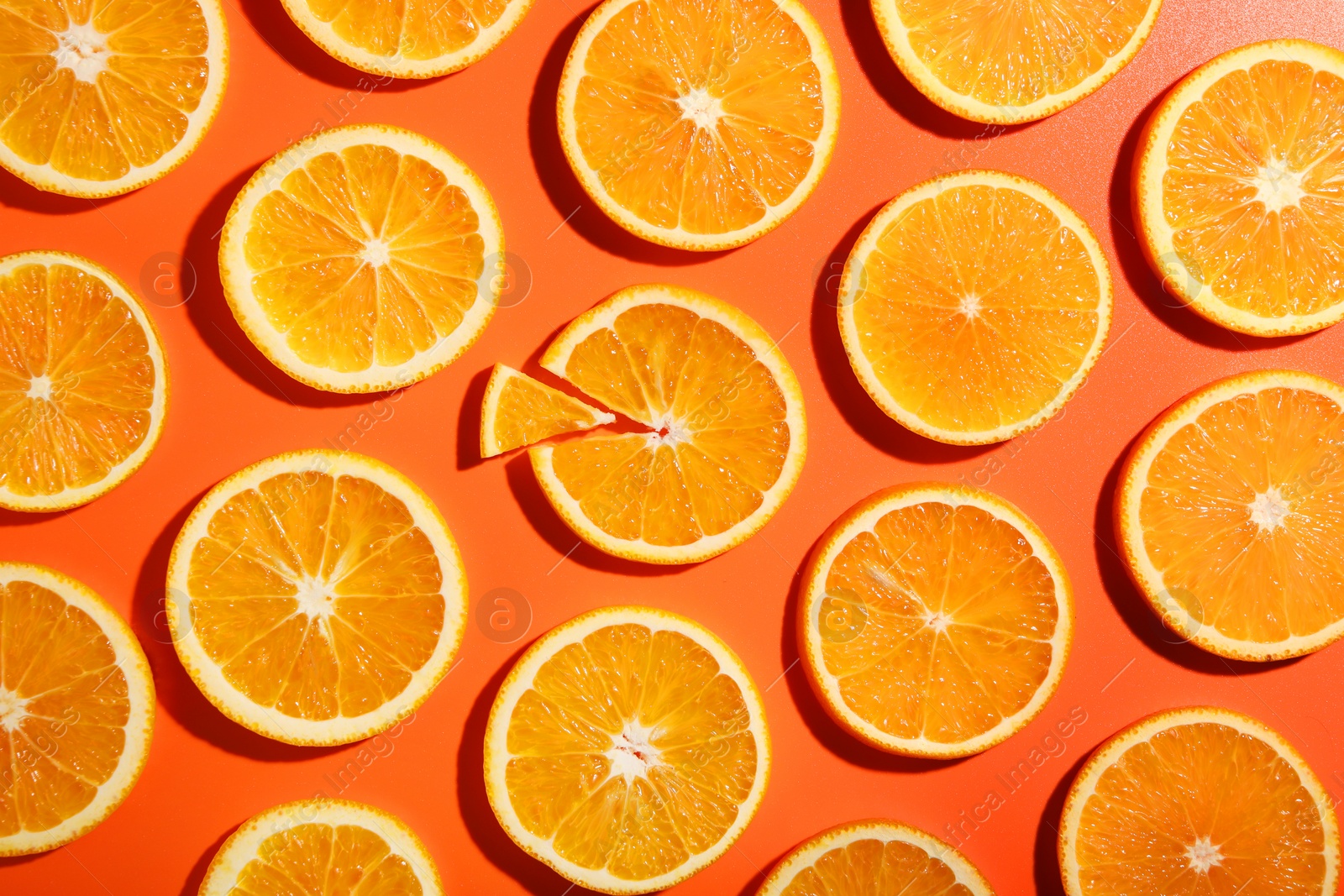 Photo of Slices of juicy orange on terracotta background, flat lay