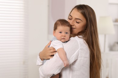 Mother holding her cute newborn baby at home, space for text