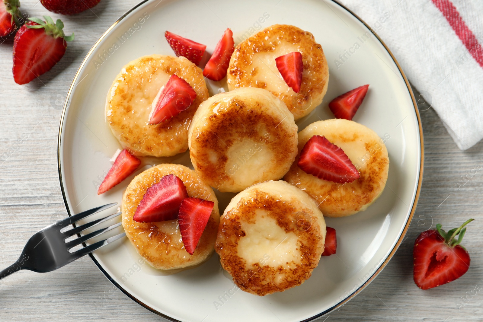 Photo of Delicious cottage cheese pancakes with strawberries and honey on white wooden table, flat lay