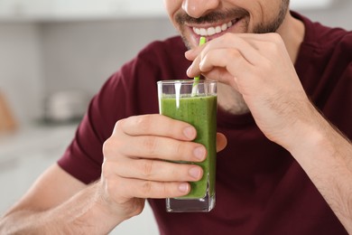 Photo of Happy man drinking delicious fresh smoothie indoors, closeup