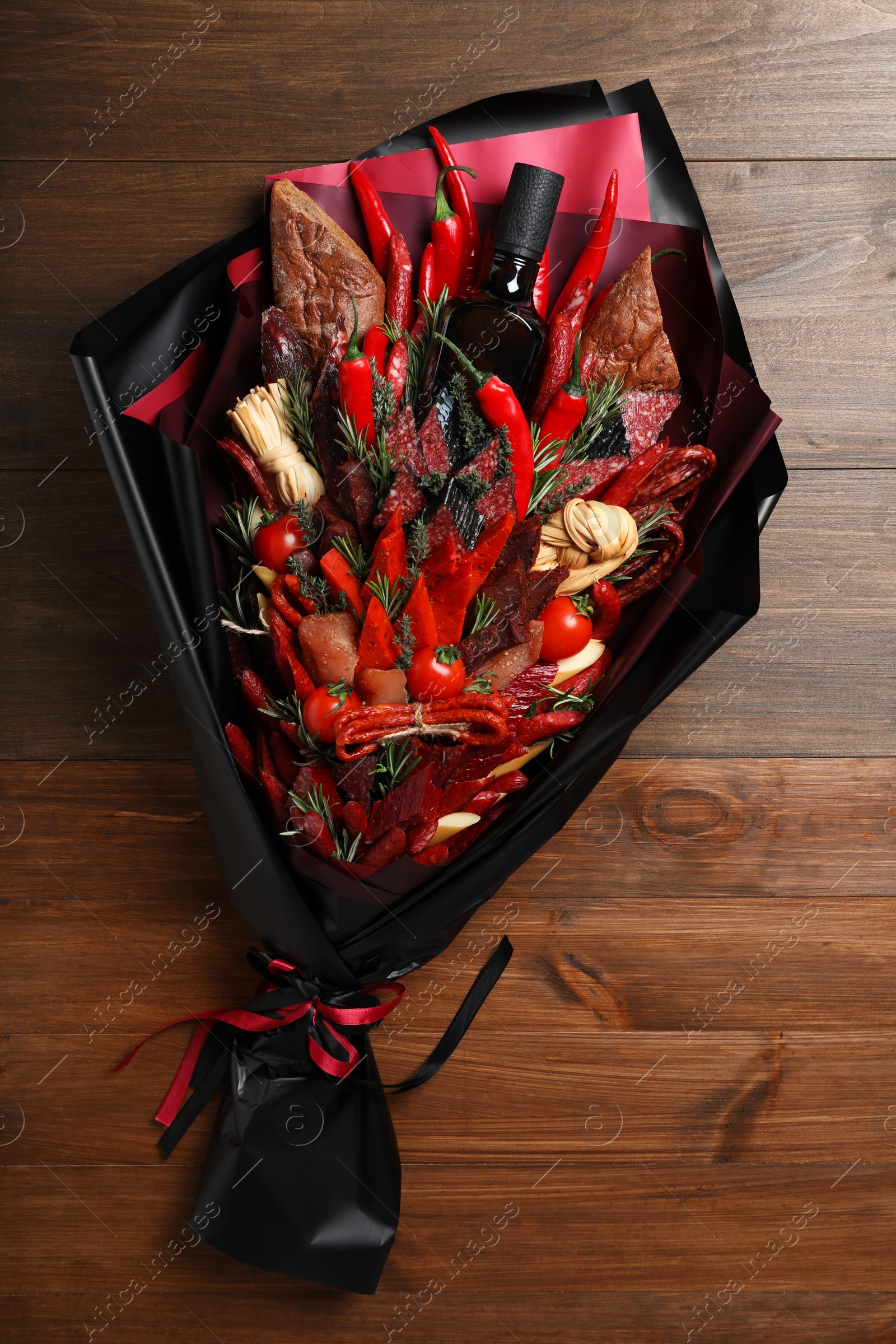 Photo of Beautiful edible bouquet with meat, cheese and vegetables on wooden table, top view