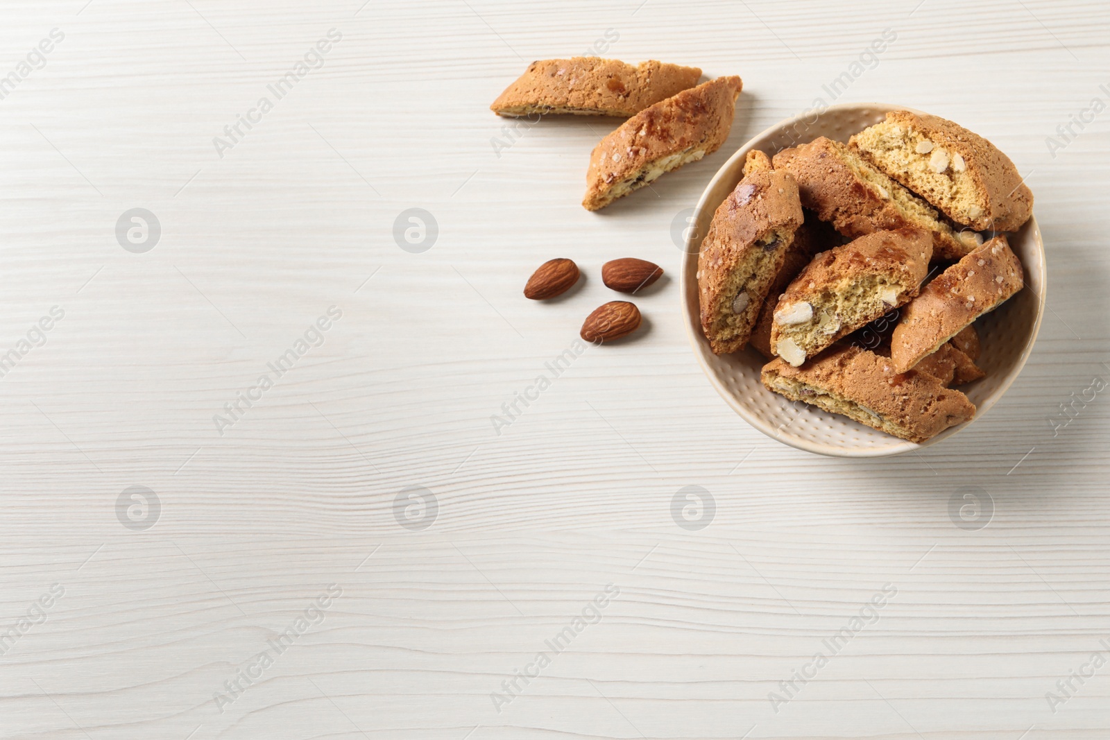 Photo of Traditional Italian almond biscuits (Cantucci) on white wooden table, flat lay. Space for text