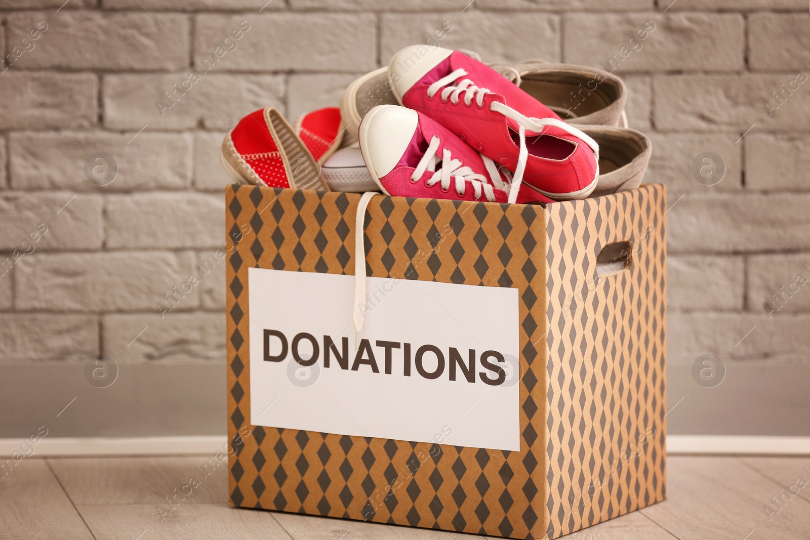 Photo of Donation box with shoes on floor against brick wall