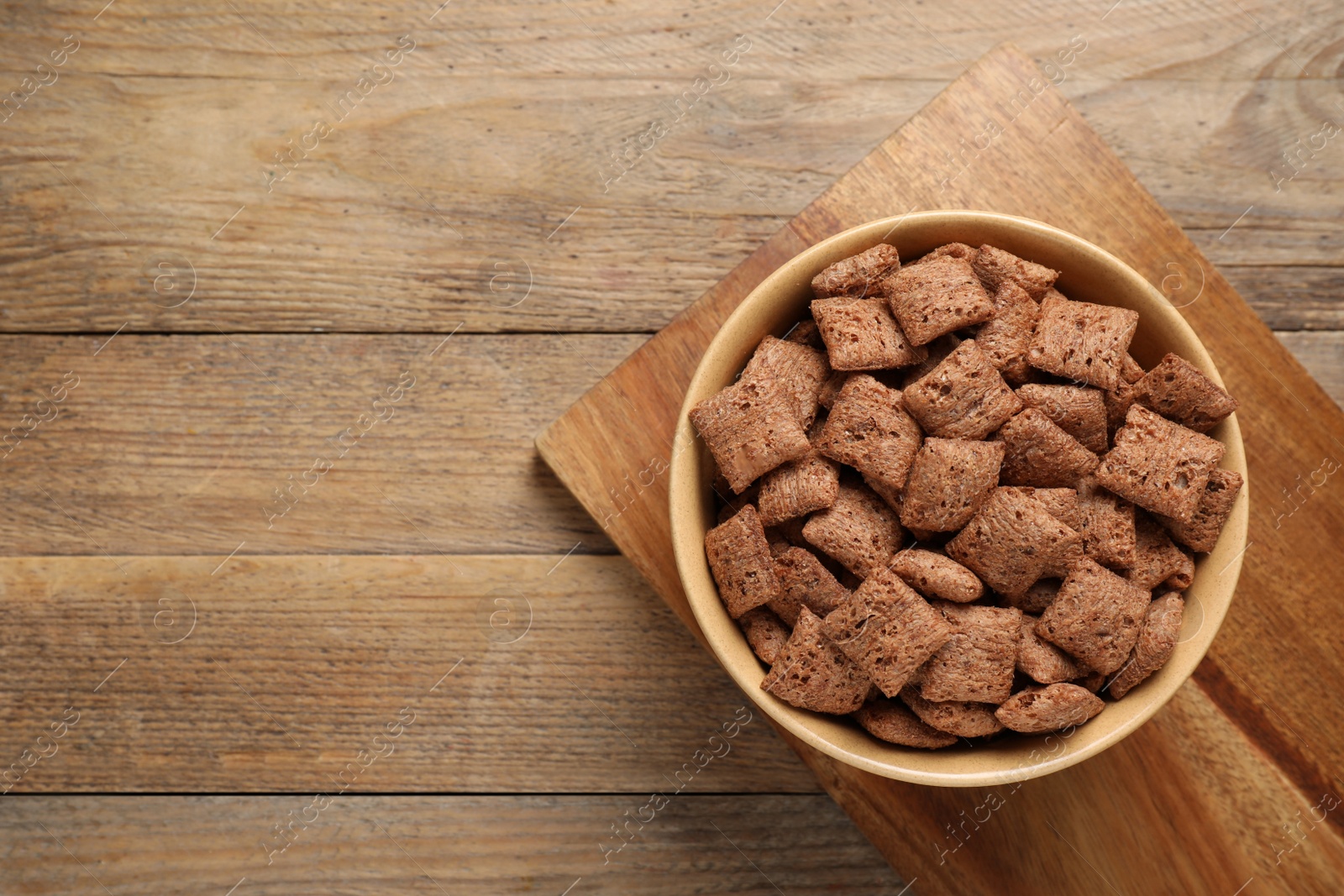 Photo of Sweet crispy corn pads in bowl on wooden table, top view. Space for text