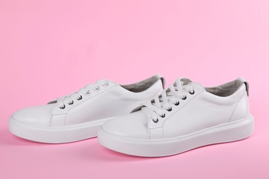 Photo of Pair of stylish white sneakers on pink background