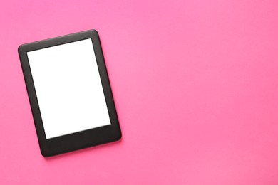 Photo of Modern e-book reader with blank screen on pink background, top view. Space for text