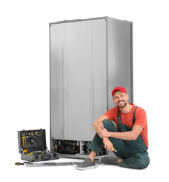 Male technician repairing refrigerator on white background