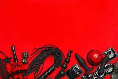 Photo of Different sex toys on red background, flat lay. Space for text