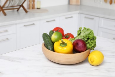 Photo of Bowl with fresh ripe vegetables and fruits on table in kitchen, space for text