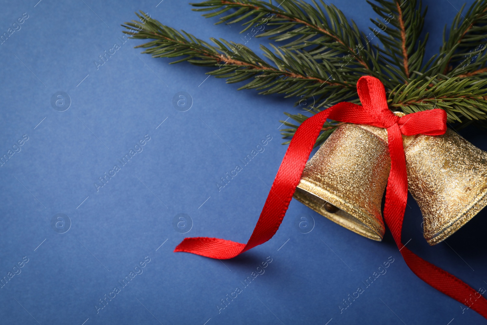 Photo of Bells and fir branches on blue background, flat lay with space for text. Christmas decor