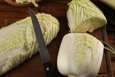 Photo of Whole and cut fresh Chinese cabbages on wooden table