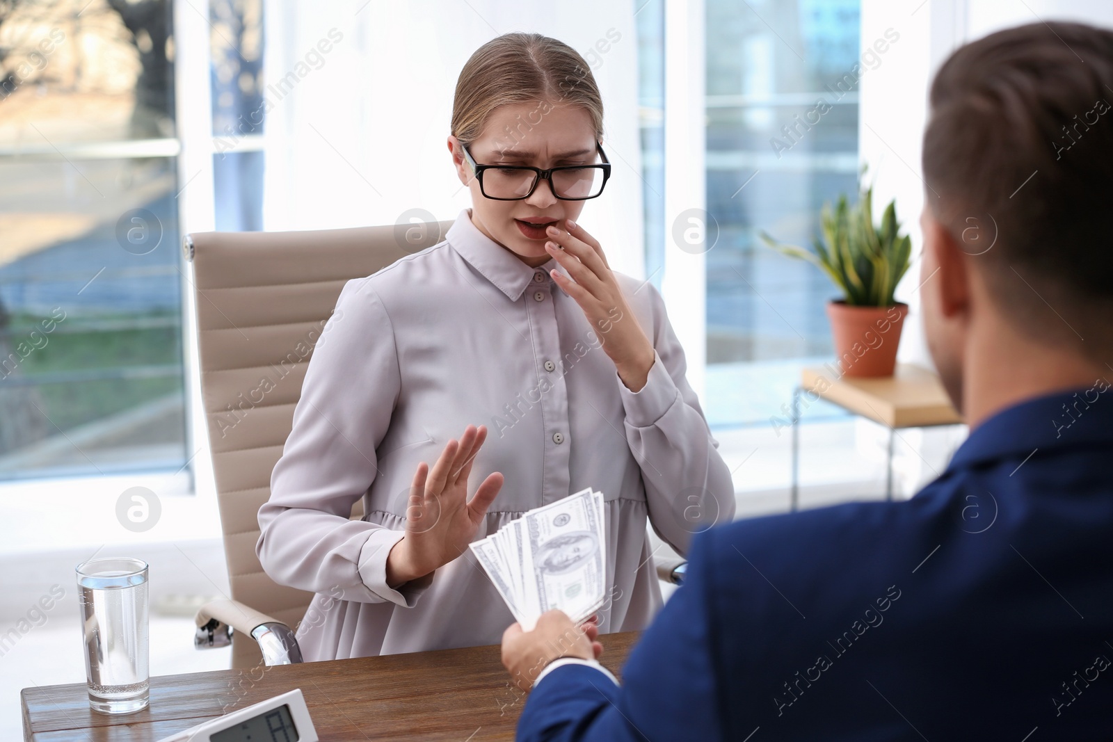 Photo of Woman refuses to take bribe money at wooden table