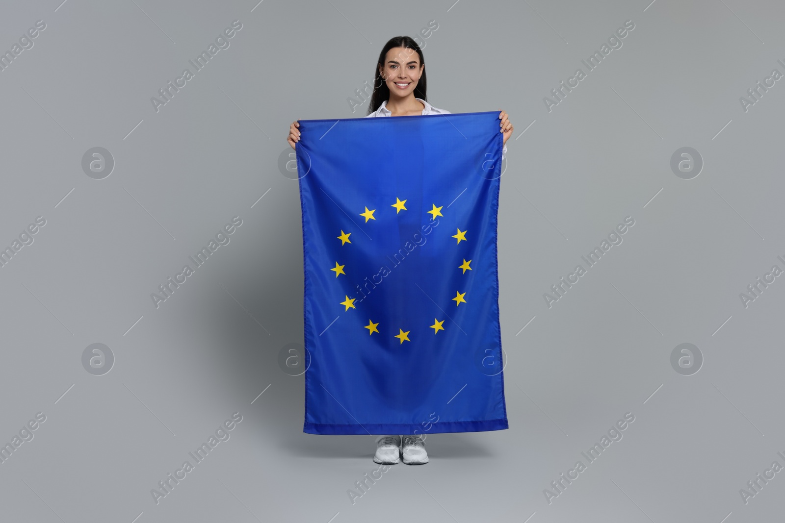 Photo of Woman holding European Union flag on light grey background