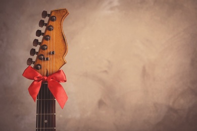 Photo of Guitar with red bow on grey background, space for text. Christmas music