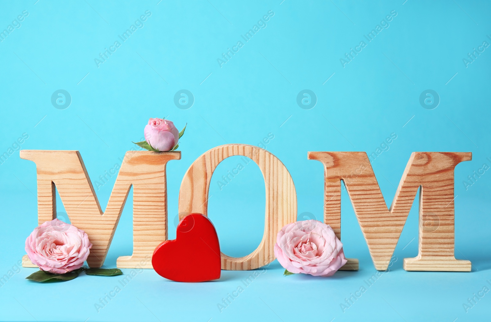 Photo of Word "MOM" made of wooden letters and flowers on color background. Happy Mother's Day