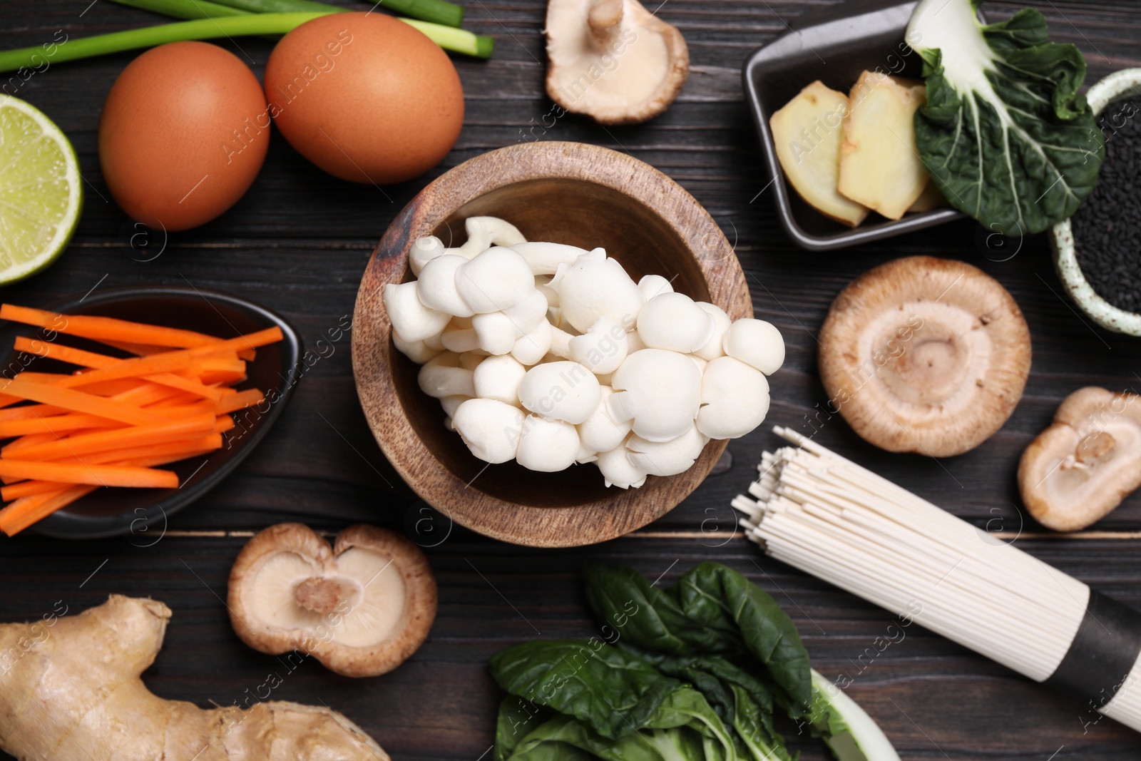 Photo of Cooking delicious ramen soup. Different ingredients on wooden table, flat lay