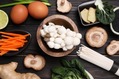 Photo of Cooking delicious ramen soup. Different ingredients on wooden table, flat lay