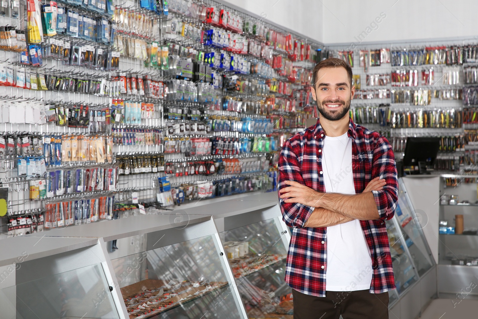 Photo of Man standing near showcase with fishing equipment in sports shop. Space for text