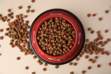 Dry dog food and feeding bowl on beige background, flat lay