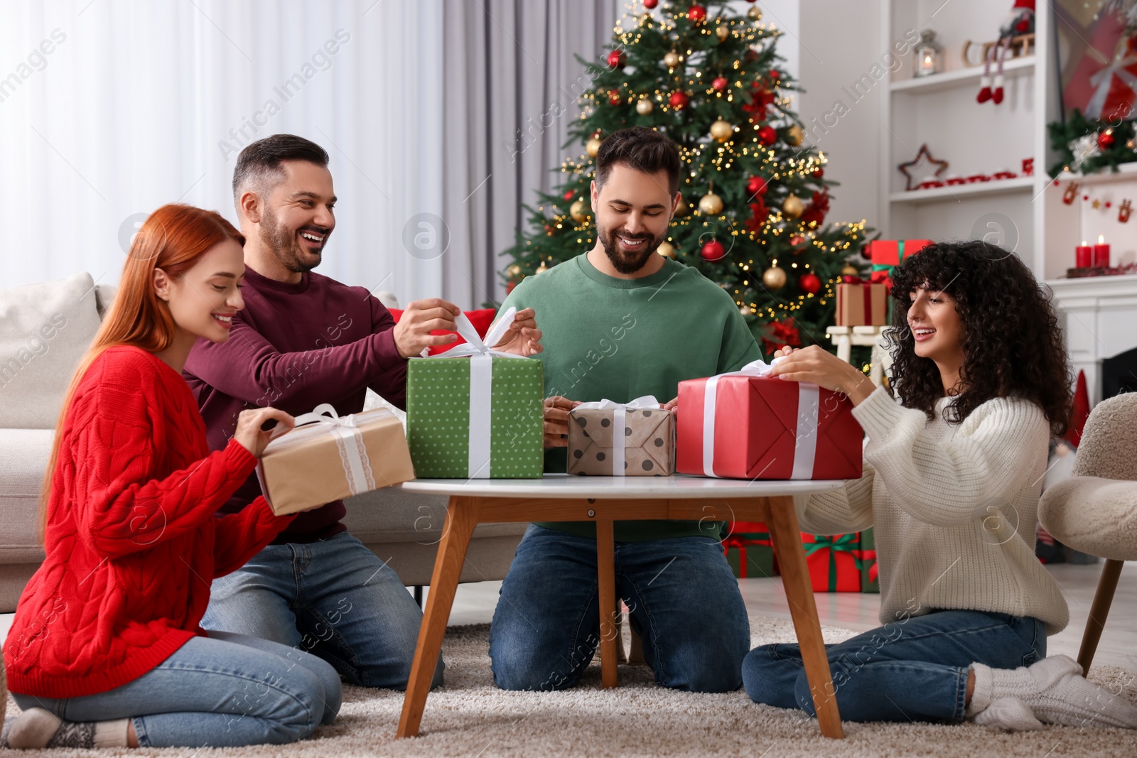 Photo of Christmas celebration in circle of friends. Women and men opening gifts at home