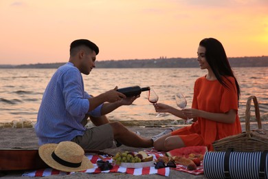 Photo of Lovely couple having picnic near river at sunset