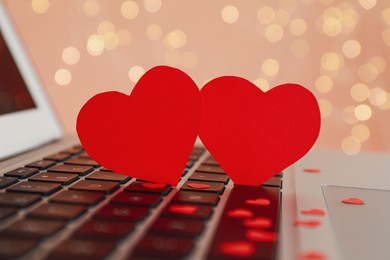 Photo of Red decorative hearts on laptop keyboard, closeup. Online dating concept