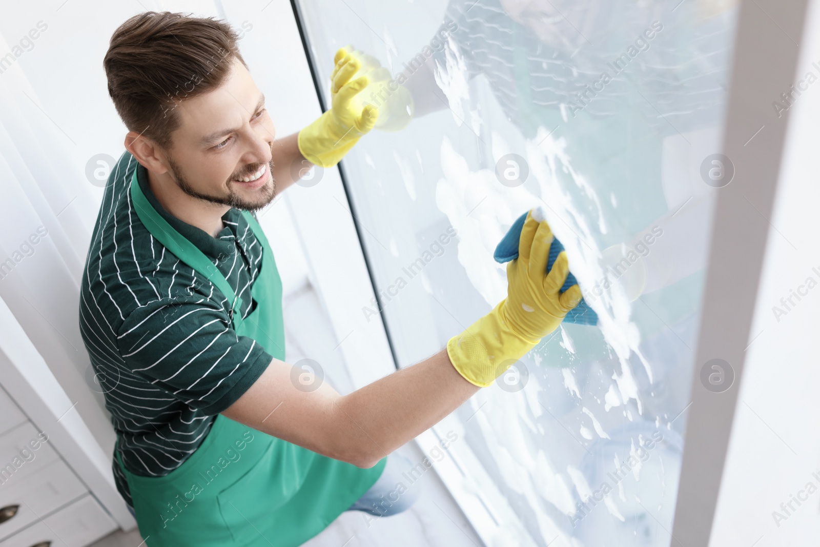 Photo of Male worker washing window glass at home