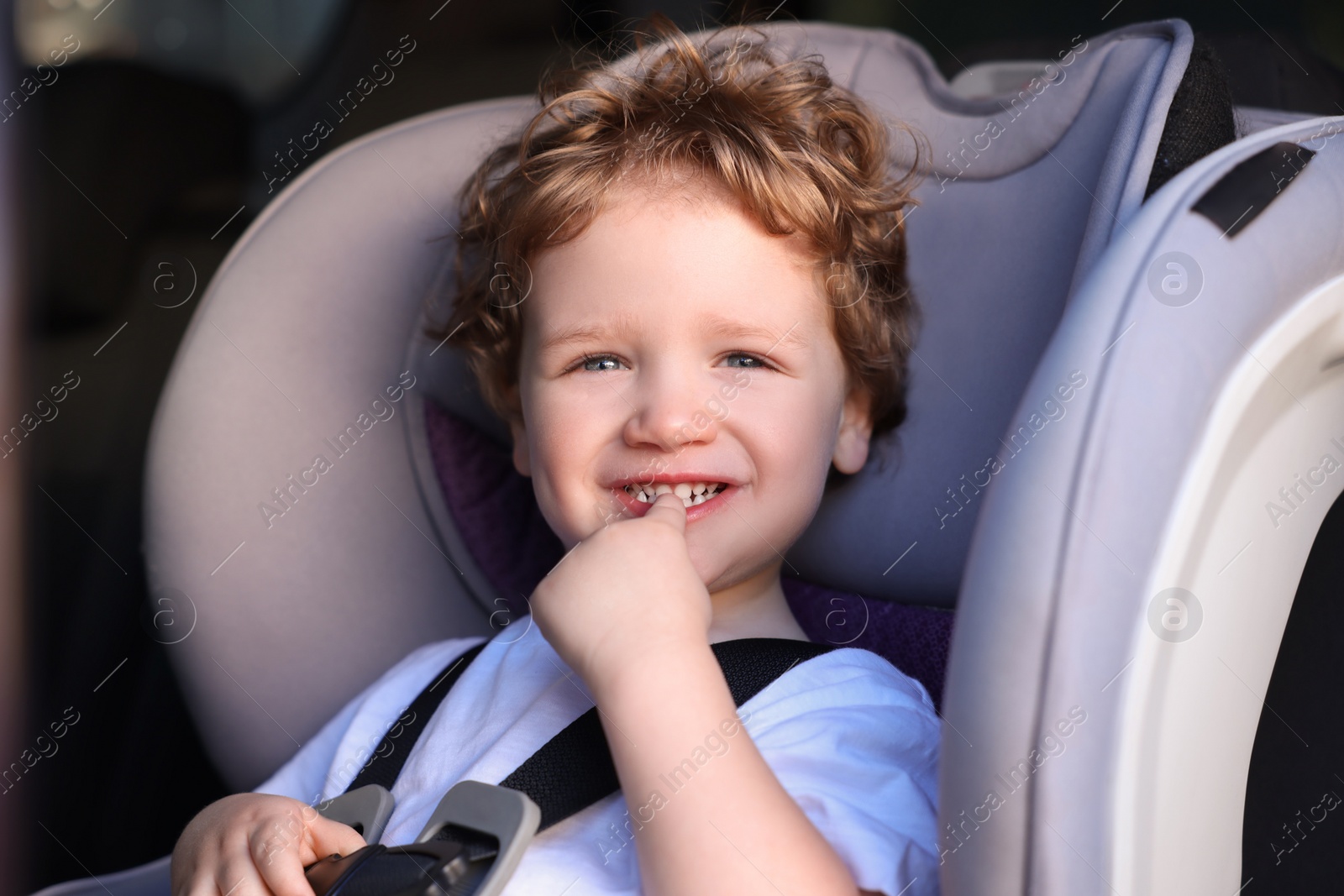 Photo of Cute little boy sitting in child safety seat inside car