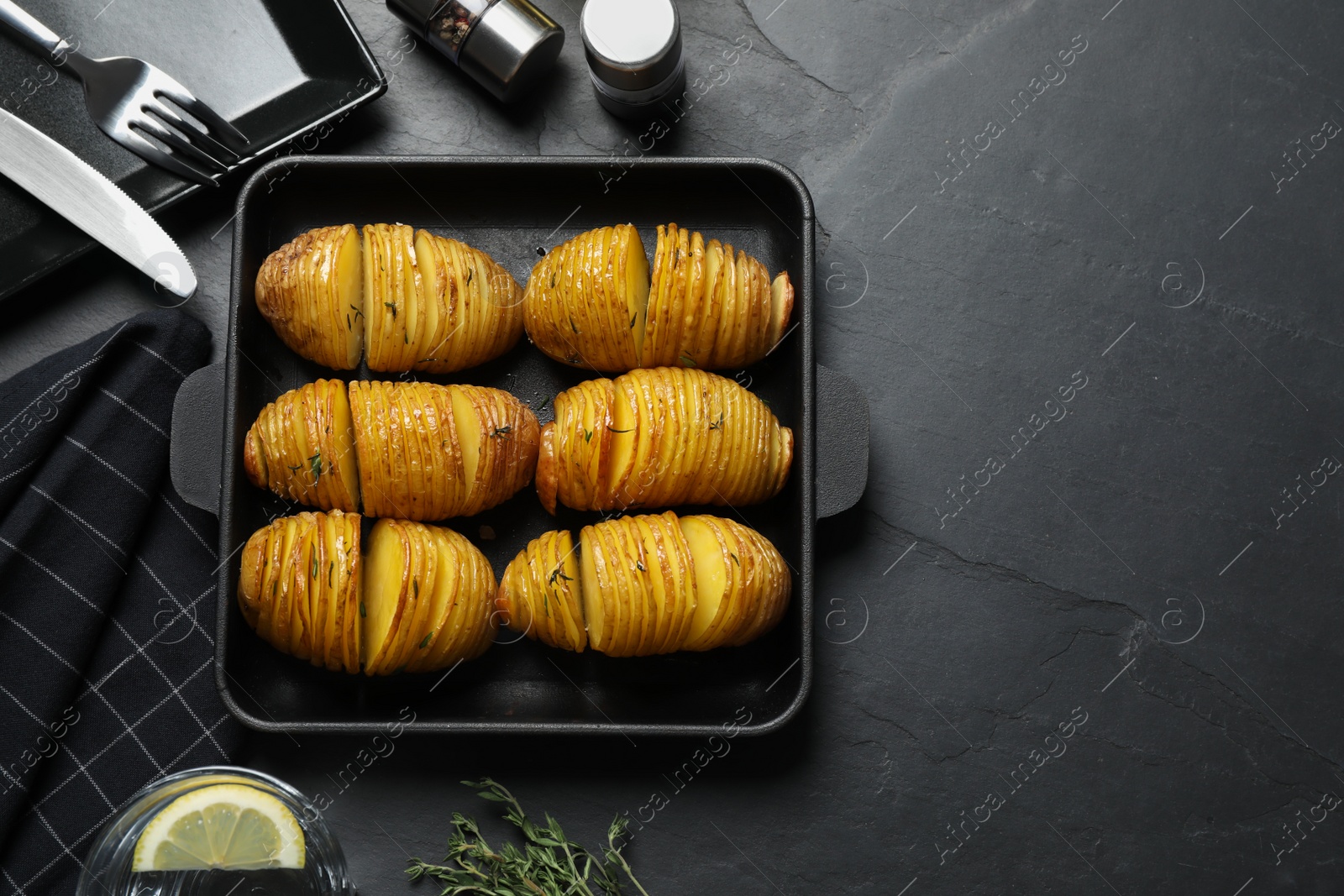 Photo of Delicious homemade Hasselback potatoes on black table, flat lay. Space for text