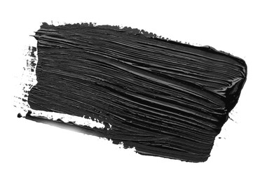 Photo of Brushstrokes of black oil paint on white background, top view