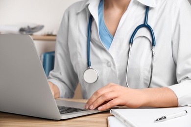 Photo of Doctor working with laptop at desk in office, closeup. Medical service