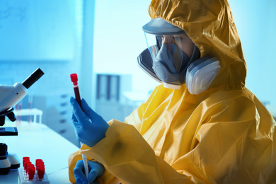 Photo of Scientist in chemical protective suit working with blood samples at laboratory, closeup. Virus research