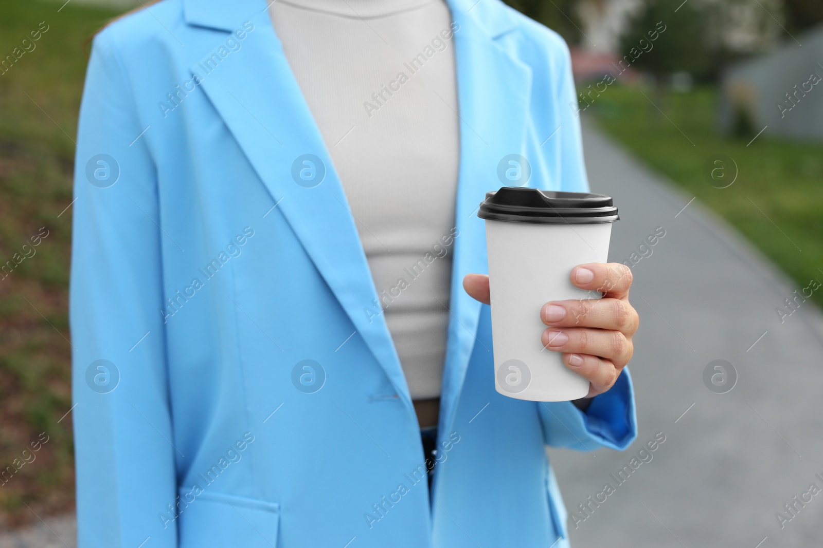 Photo of Coffee to go. Woman with paper cup of drink outdoors, closeup