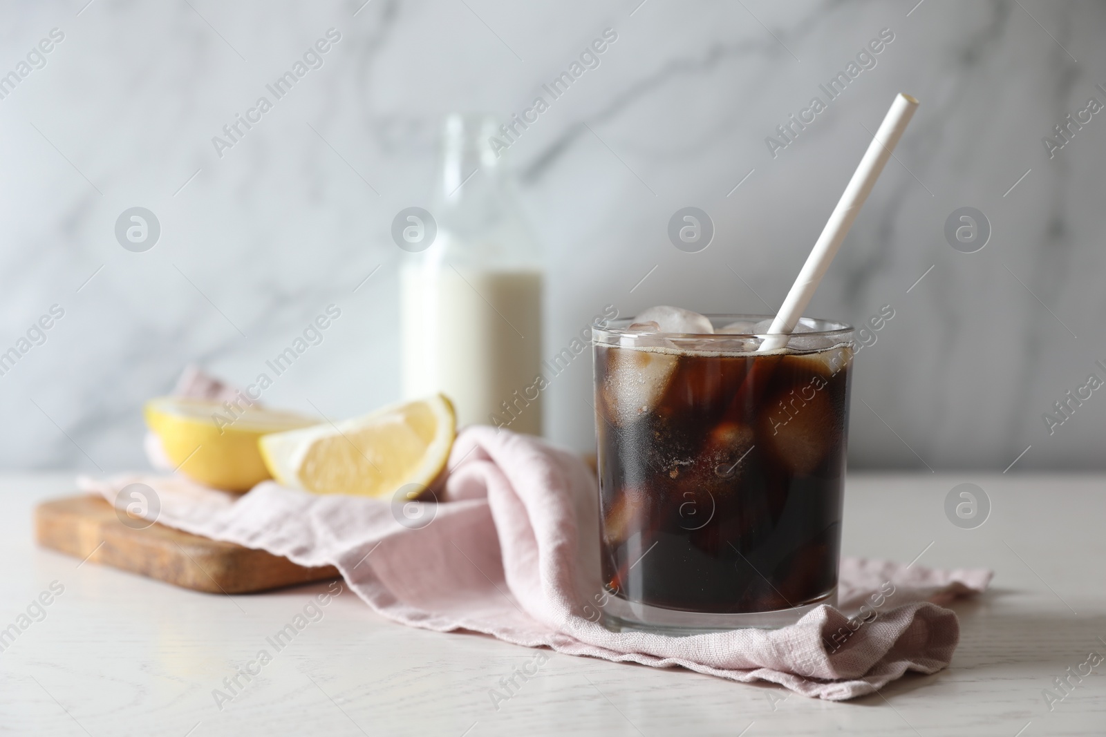 Photo of Refreshing iced coffee in glass on white wooden table